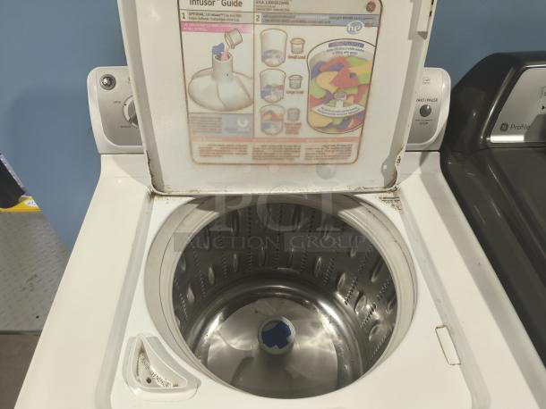 GE 4.1 cu ft top-load washer, model WHRE5550K2WW. Features high-efficiency drum, control settings. Visible wear on lid edge.