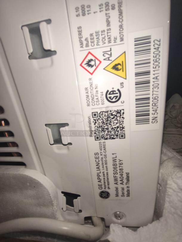 BRAND NEW GE 6,000 BTU Window Air Conditioner, Model AWFS06BWL1, scratch and dent condition, with safety labels visible.