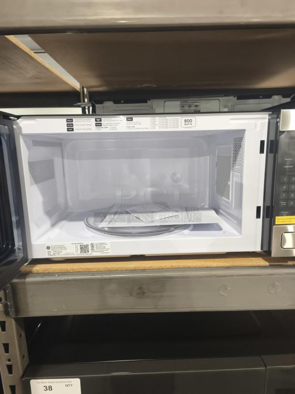 BRAND NEW SCRATCH AND DENT GE Profile PEM31SFSS 1.1 cu ft Countertop Microwave Oven, open door, interior with labels showing 800 watts.