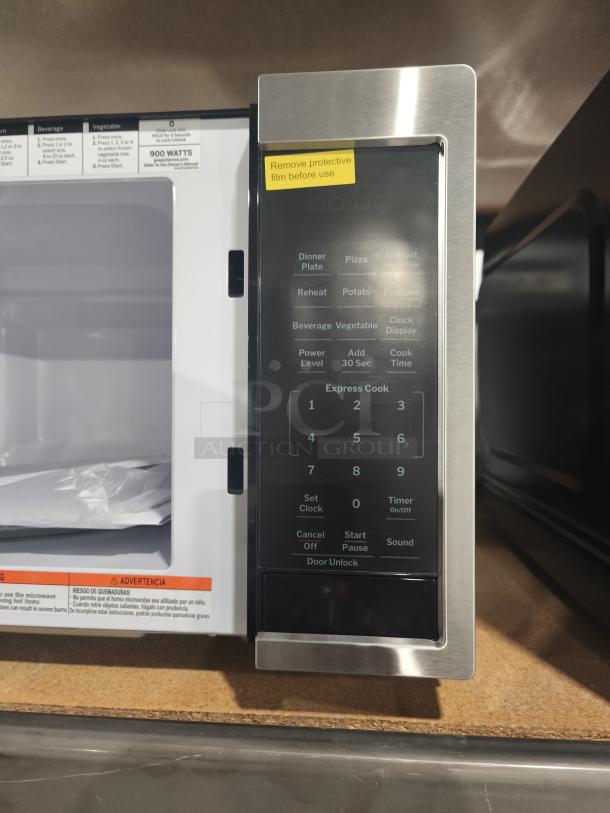 BRAND NEW GE GCST09N1WSS countertop microwave, 0.9 cu ft, stainless steel, touchpad, protective film note visible.