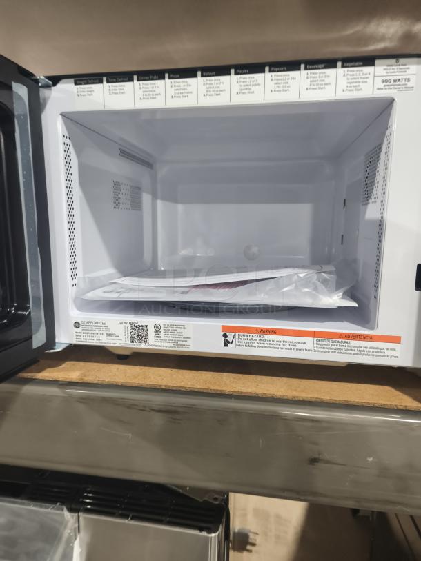 BRAND NEW SCRATCH AND DENT GE 0.9 cu ft countertop microwave oven, model GCST09N1WSS. Interior labels with instructions visible.