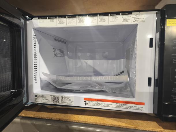 BRAND NEW GE 1.1 Cu. Ft. Countertop Microwave, Model GCST11N1WSS. Interior view, 900 watts, visible labels.
