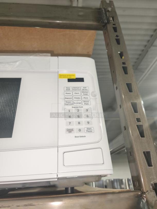 BRAND NEW GE 1.1 Cu. Ft. Countertop Microwave, Model GCST11N1WWW, Scratch and Dent, keypad close-up with protective film label.