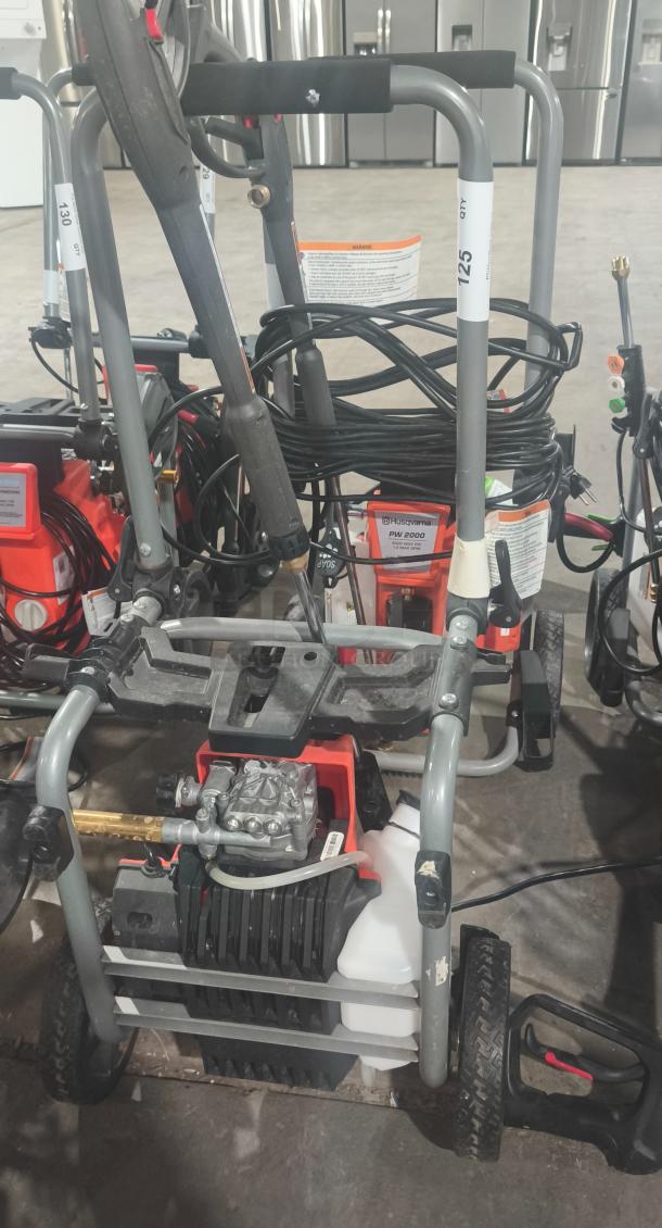 Husqvarna PW2300 electric pressure washer, tested and working. Features durable frame, hose reel, labeled for easy use.