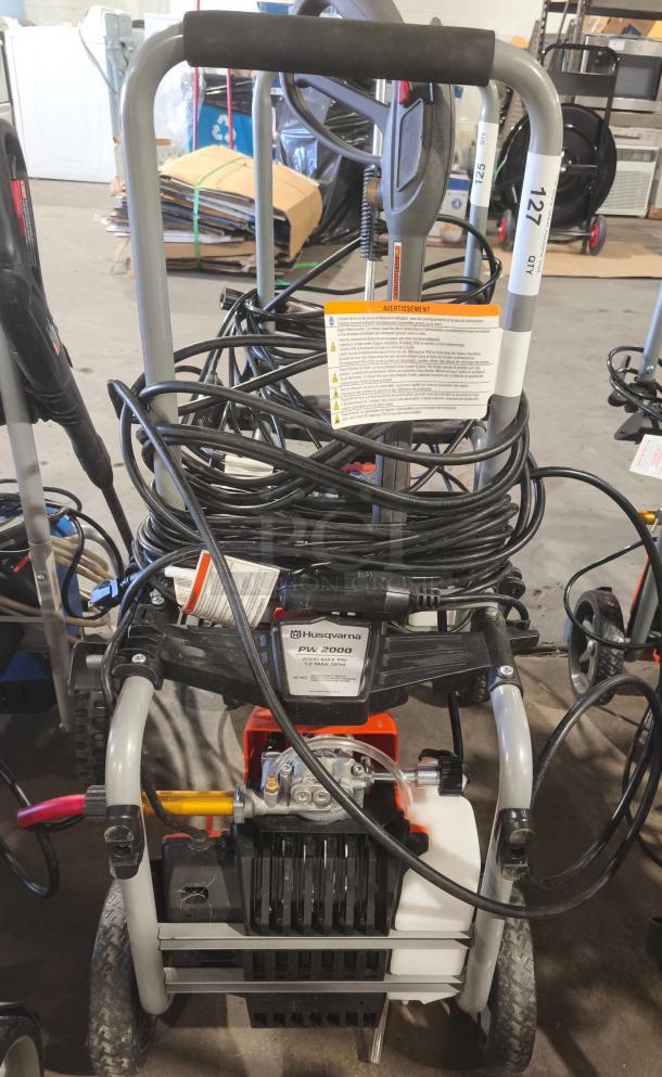 Husqvarna PW2300 Electric Pressure Washer, tested and working, features sturdy frame, hose storage, and user manual.