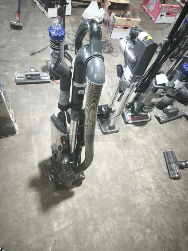 Shark UV550 Lift-Away XL Upright Vacuum, tested and working, shown in a storage area, features extended hose and upright build.