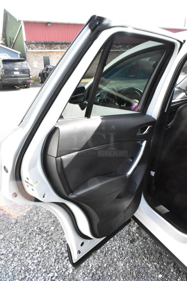 2016 Mazda CX-5 Grand Touring 4WD in white, rear passenger door open, black interior, visible door panel controls.