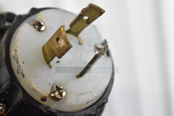 Close-up of an electrical plug showing prongs and screws, mounted on a plastic base with UL safety markings visible.