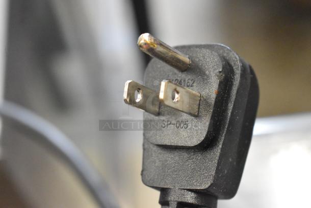 Close-up of a power plug for the Follett 7UD112A-IW-NF-ST-00 ice maker and water dispenser, showing electrical prongs.