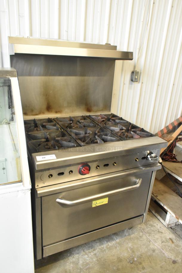 Qualite stainless steel 6-burner commercial gas range with oven, overhead shelf, and backsplash. Good condition.
