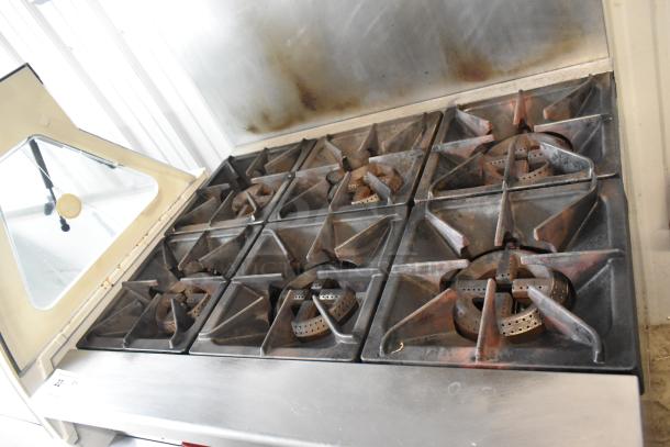 Qualite stainless steel 6 burner gas range with oven, over shelf, and backsplash. Slightly used condition.