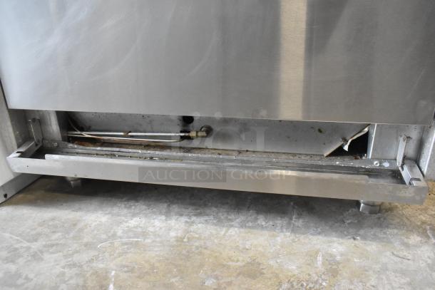 Qualite stainless steel 6-burner commercial gas range with oven, over shelf, and backsplash. Visible wear and dirt underneath.
