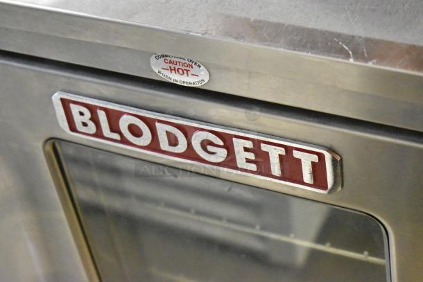 Blodgett stainless steel commercial gas convection oven, half size, with view-through door, metal racks, thermostatic controls. Caution label visible.