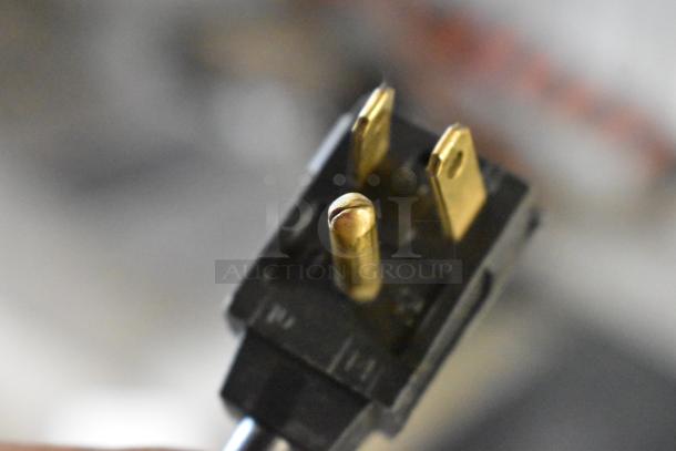 Close-up of a power plug for a General Electric Monogram ZDIS15SSHRHA stainless steel ice machine, showing gold prongs.