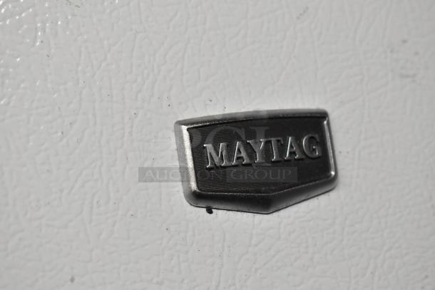 Close-up of Maytag logo on a white textured surface, part of the Maytag M1TXEGMYW01 cooler/freezer.