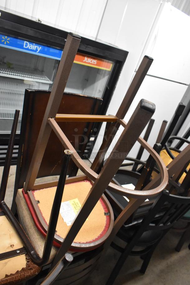 19 stacked brown and black chairs with cushioned seats, some wear visible, offer includes 19 chairs. Labels on some chairs.