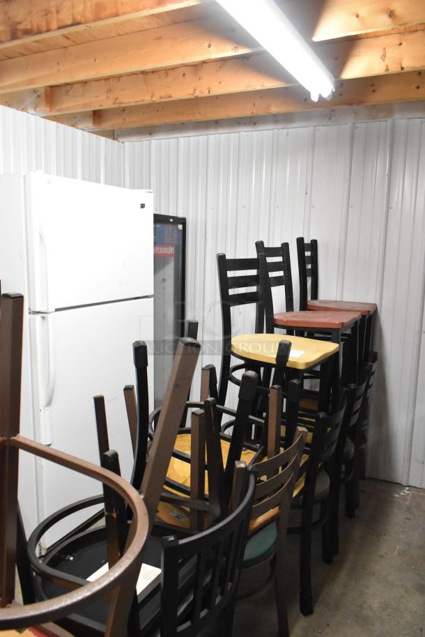 19 assorted chairs stacked, featuring wood and metal designs. Varied conditions. Includes stools and dining chairs.