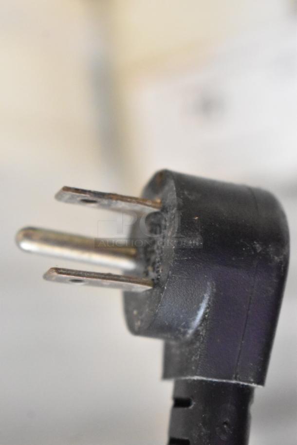 Close-up of a three-prong power plug, indicating use with the Delfield 4460N-24M-QZN Stainless Steel Commercial Prep Table.
