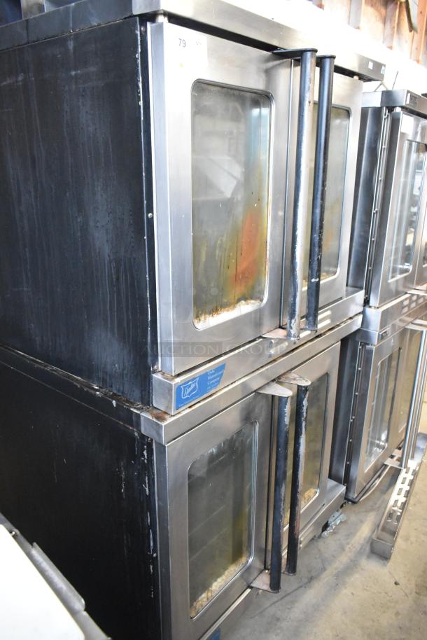 Duke stainless steel commercial convection ovens with view-through doors, metal racks, and thermostatic controls. Visible wear.