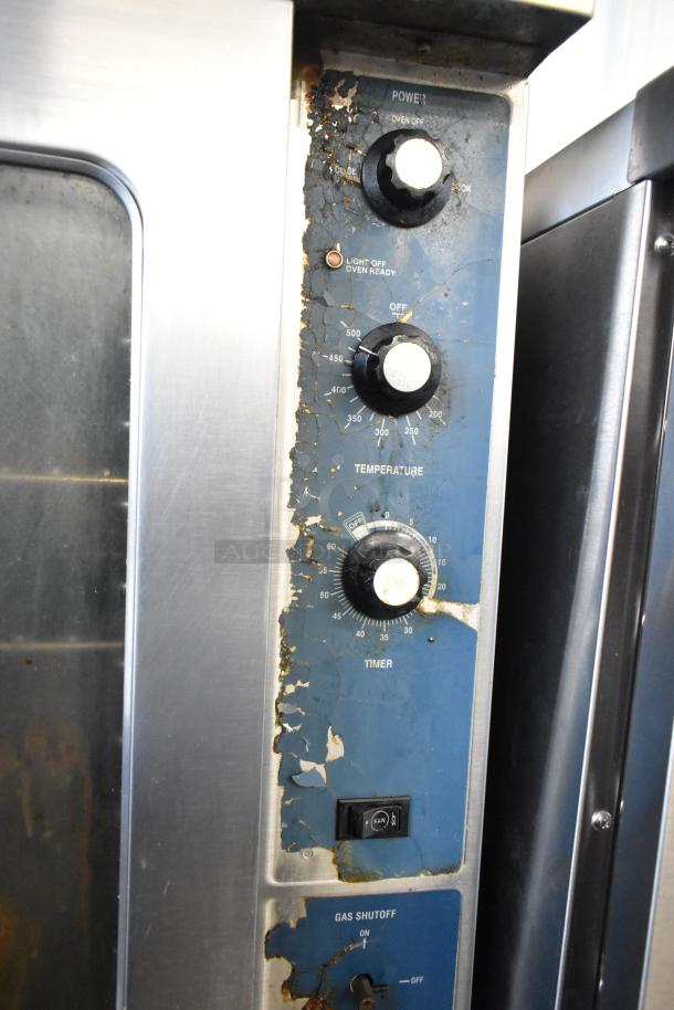"Duke stainless steel commercial convection oven panel with dials for power, temperature, timer, and gas shutoff, showing wear."