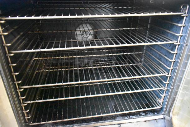 Duke stainless steel convection oven with view-through doors, metal racks, and thermostatic controls. Interior racks visible.