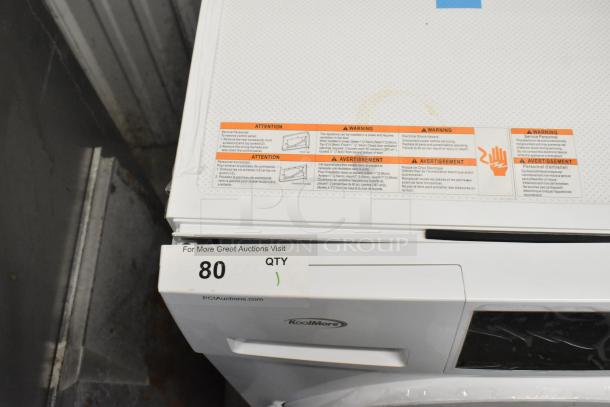 Brand new KoolMore front load washer with minor scratches and dents, visible KoolMore logo, and safety warning labels.