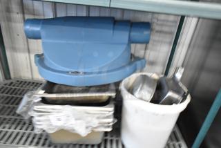 6 brand new scratch and dent items including stainless steel drop-in bins, blue component on top, stored on metal shelf.