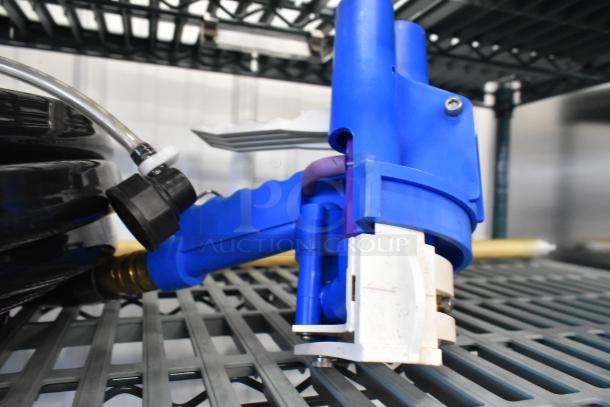 Blue hose with attached nozzle, brass connection, and black plastic fitting, shown coiled on metal shelving.