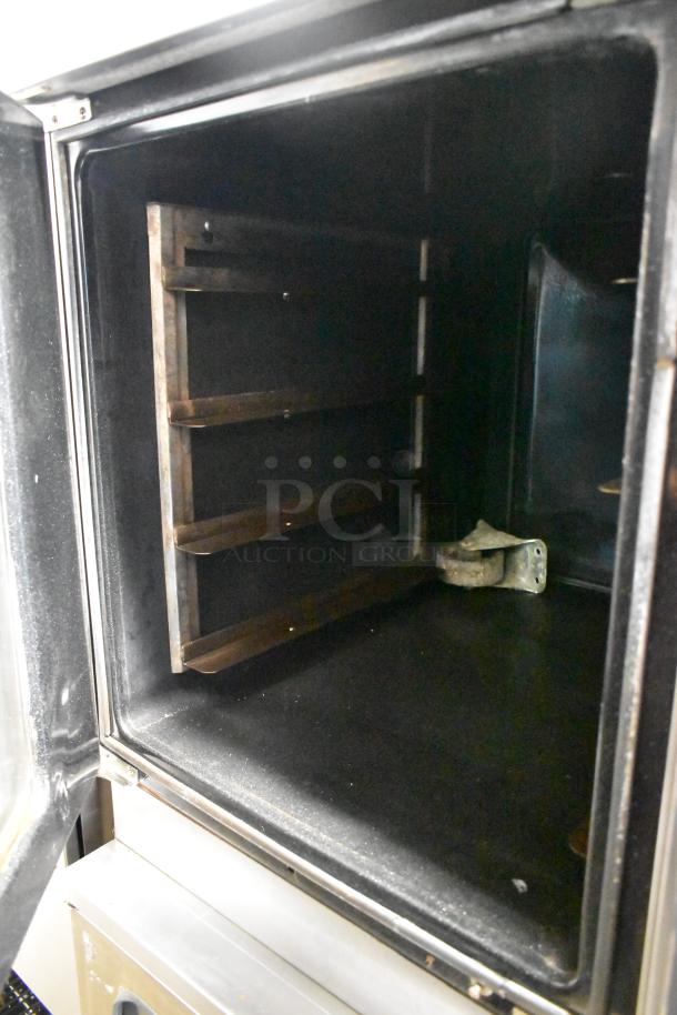 Moffat E89AMS stainless steel proofer cabinet interior, metal oven racks, open door view, commercial casters visible.