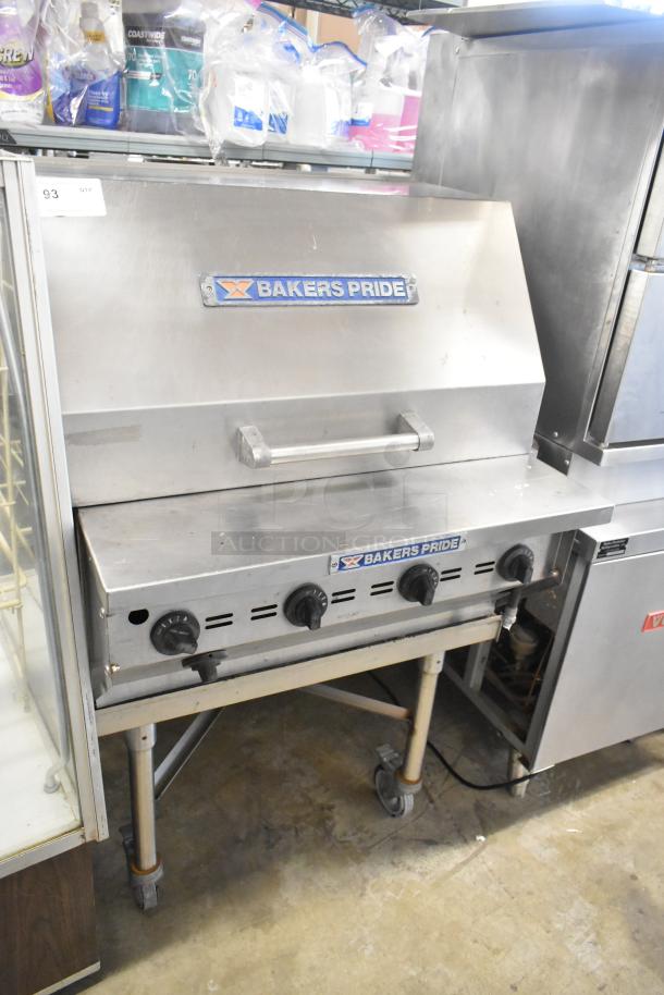 Bakers Pride stainless steel propane charbroiler grill with cover, commercial casters, and control knobs, in good condition.