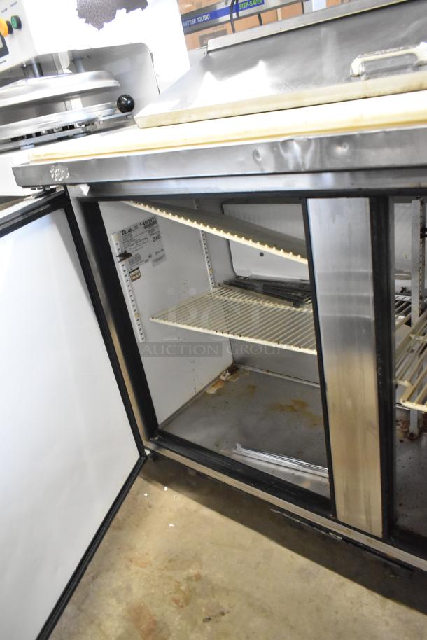 True TSSU-48-12 stainless steel sandwich prep table, showing open interior with two wire shelves; slightly worn condition.