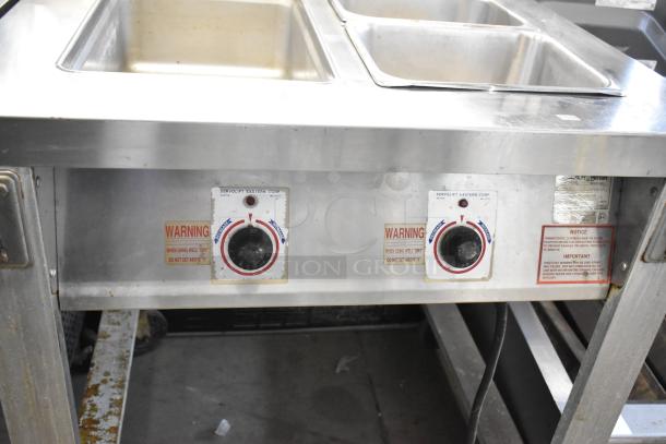 Servolift Eastern 501-2 stainless steel electric steam table on casters, dual controls, used condition, warning labels visible.