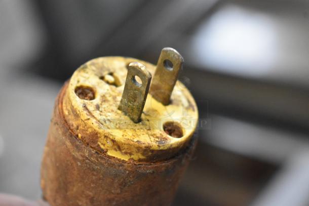 Close-up of a rusty electrical plug with two prongs, showing signs of wear and oxidation.