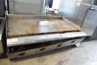 Stainless steel countertop propane gas griddle, commercial use, flat top, visibly used, two control knobs.