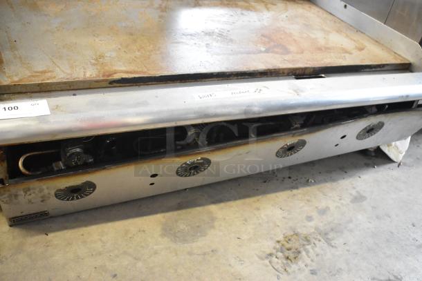 Stainless steel commercial countertop propane gas flat top griddle with four control knobs, visible wear on cooking surface.