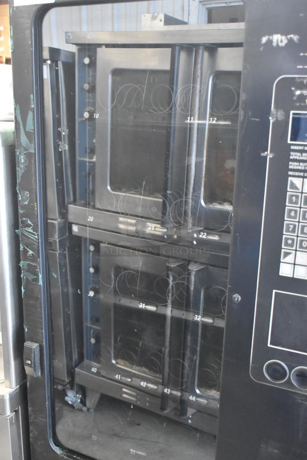 Metal commercial floor-style vending machine with spiral coil dispensers. Features keypad controls. Used condition.