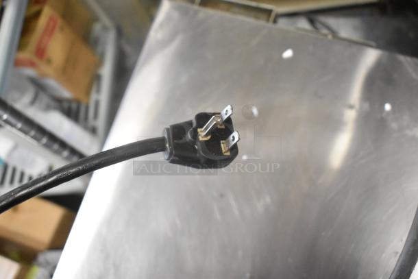 Close-up of a power plug from unspecified item, against a metallic surface background.
