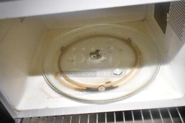 Interior view of a used microwave oven with a glass turntable, showing signs of wear and discoloration.