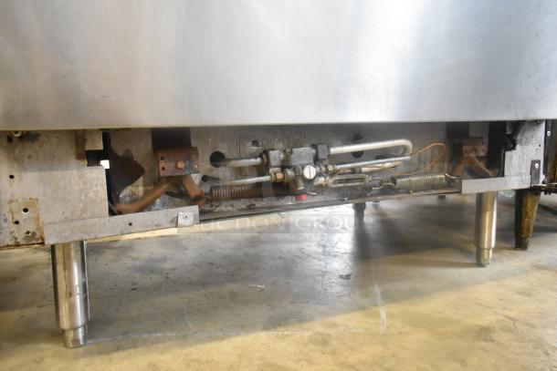 Vulcan stainless steel commercial gas griddle with 2-burner range, oven, and salamander cheese melter. Gas lines visible.