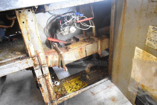 Frymaster FM245ESC fryer interior, showing natural gas connections and components, with signs of wear and use.