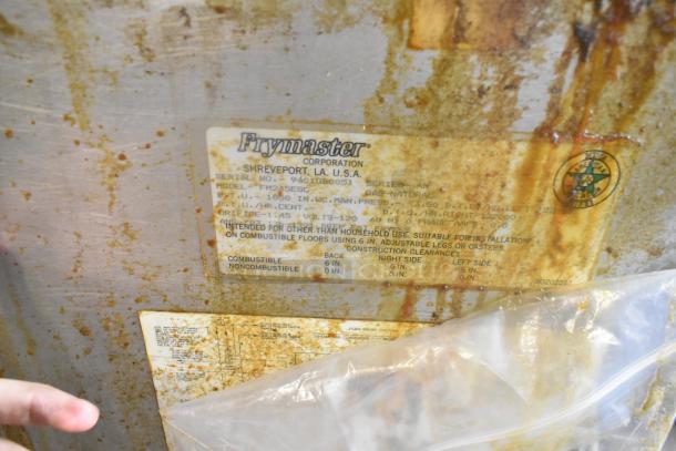 Frymaster FM245ESC fryer label, showing model, serial number, 122,000 BTU, and natural gas specs, on stainless steel surface.