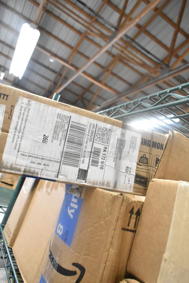 Cardboard boxes, including labeled glass cleaner and monitor bracket, stacked on a metal shelf in a warehouse.