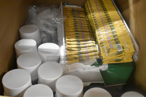 Box of mixed items including Rubbermaid Auto Foam and glass cleaner; multiple sealed packets and white containers visible.