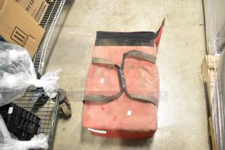 Red insulated food carrying bag with black straps, showing signs of wear. Suitable for food transport.