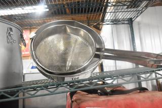 Two metal China cap strainers on a shelf, in good condition, with perforated surfaces and long handles. Auction tag reads "166".