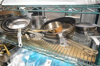 16 assorted metal skillets and stock pot on a shelf, used condition. Bid covers all items.