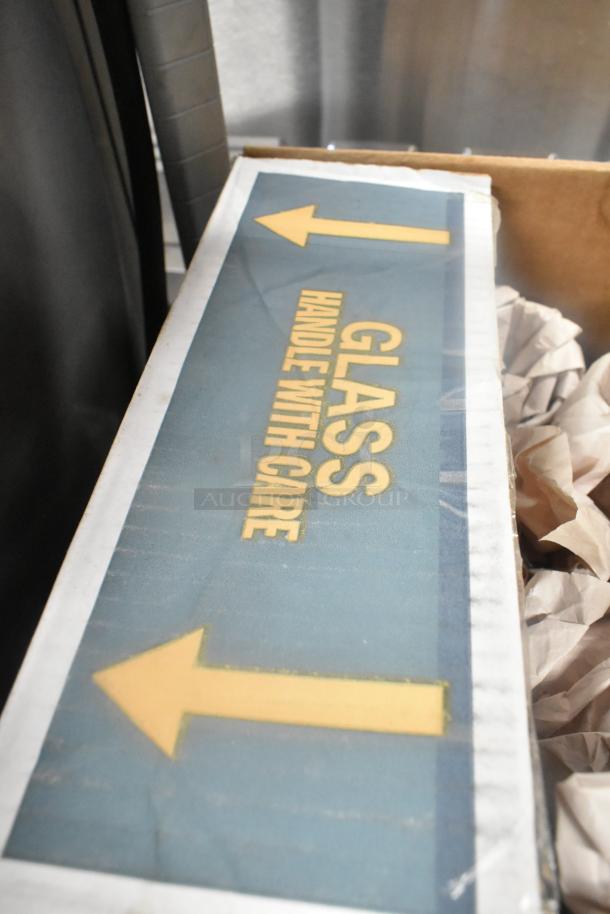 Box labeled "GLASS HANDLE WITH CARE" containing 7 items including glasses, packed with paper for protection.