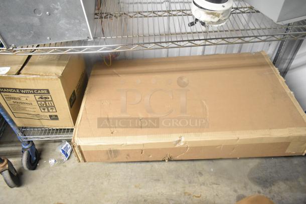 Cardboard box marked "Globe 6000018" on shelf, contents include a diaper changing station. Box shows wear, handle with care.