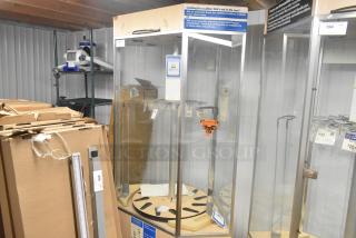 Glass merchandiser display case with metal frame, rotating shelves, and visible labels. Good condition with minor wear.
