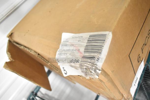 Cardboard box containing a scratch and dent market umbrella, visible shipping label with barcode and damaged corner.
